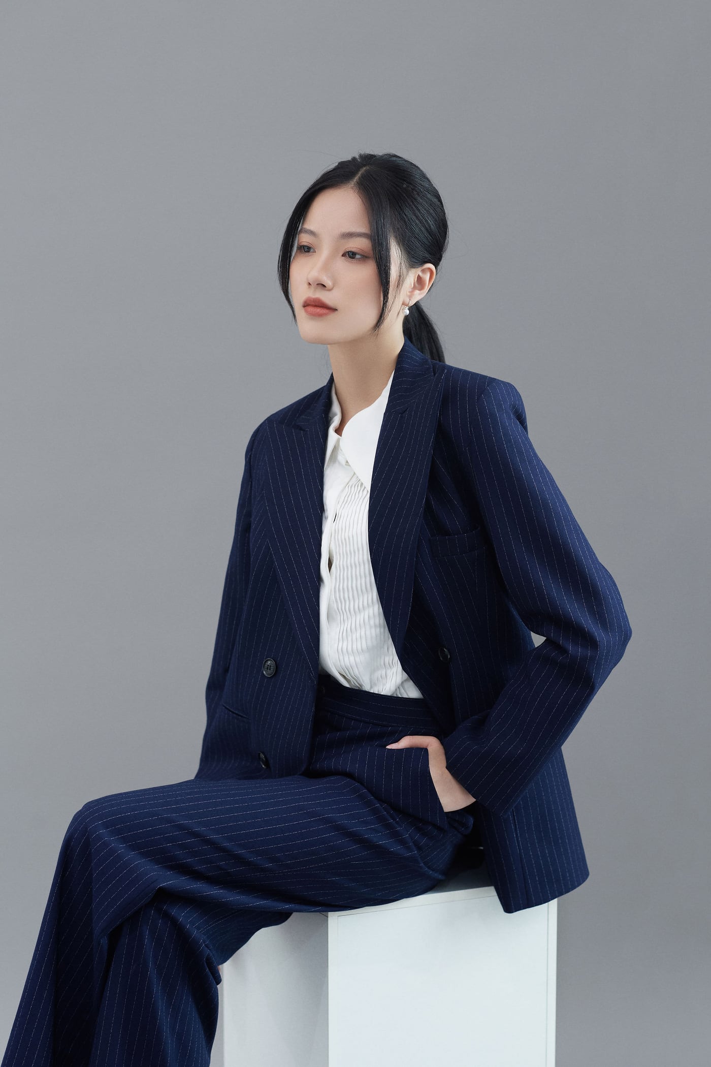 Ảnh profile cơ bản nữ mặc vest sọc ngồi tạo dáng trong studio